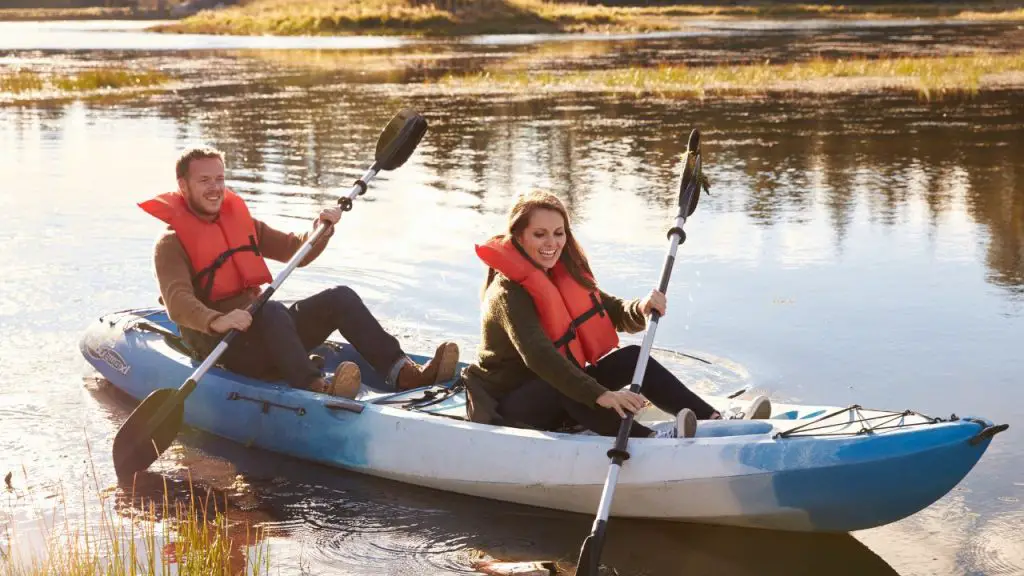 A couple  is rowing blue kayak