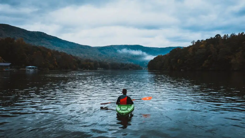 he is kayaking in the middle of the lake