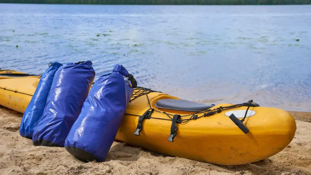 Waterproof bags standing by yellow plastic kayak