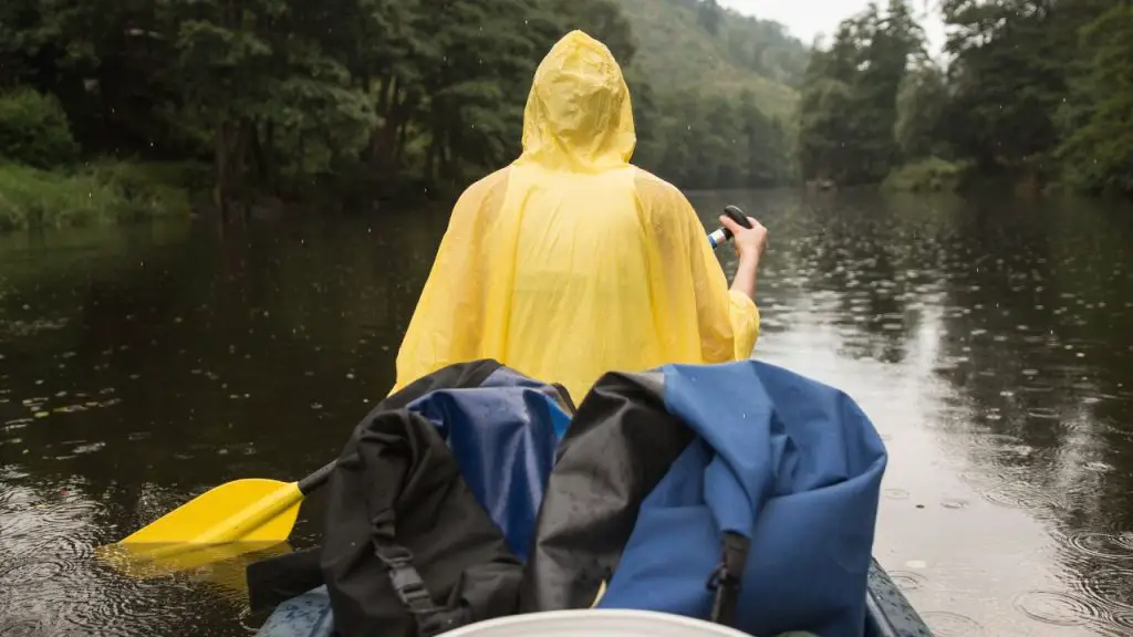 Young woman kayaking the river in the rain