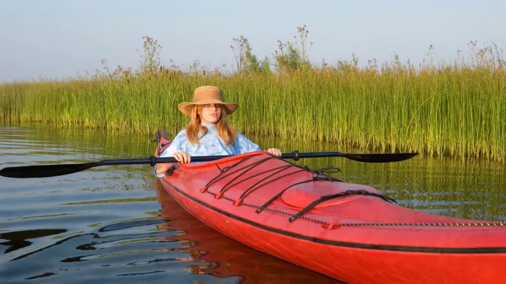  a girl is rowing a red kayak
