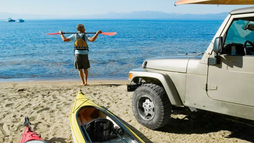 man standing with his boats and car