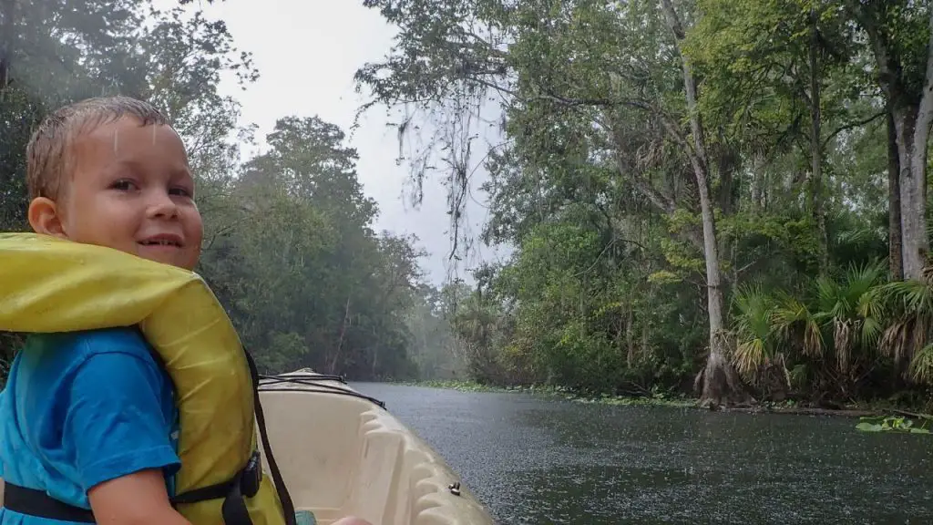 young boy is kayaking in the rain