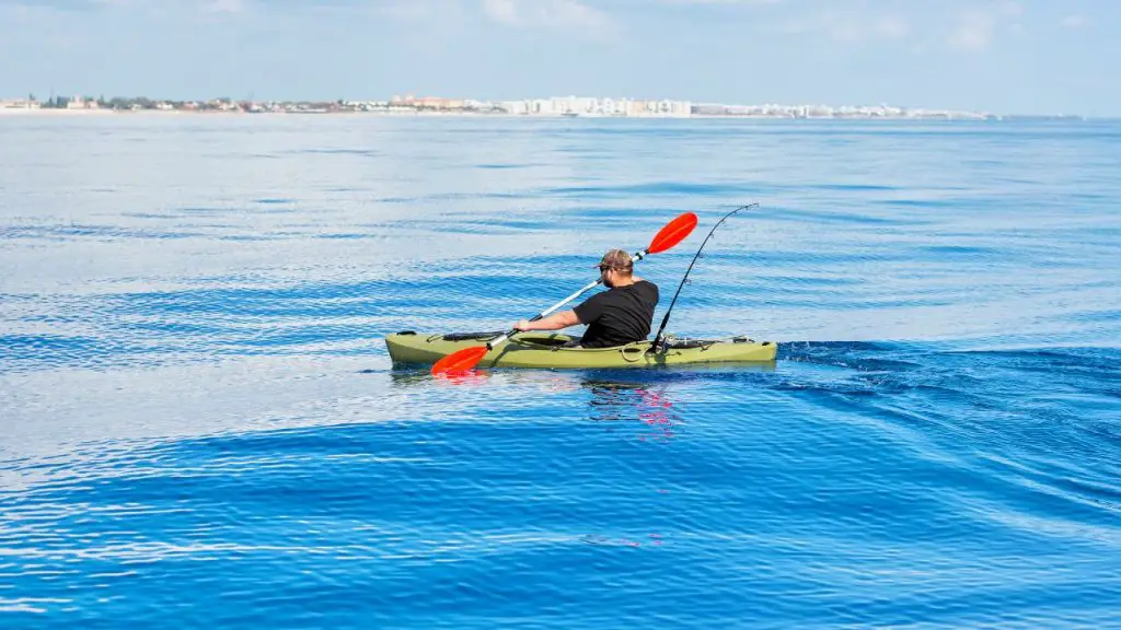 A man is paddling a fishing kayak