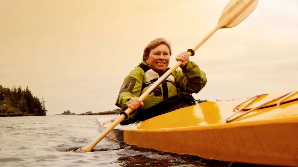 A woman is kayaking on the yellow kayak