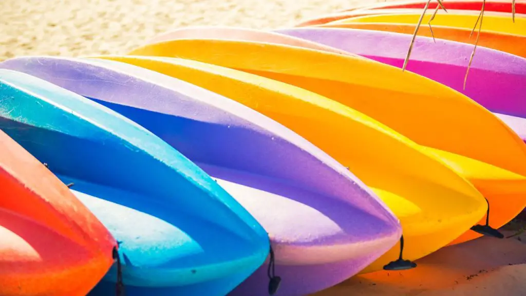 Colorful kayaks are lying on the sand in the sunshine