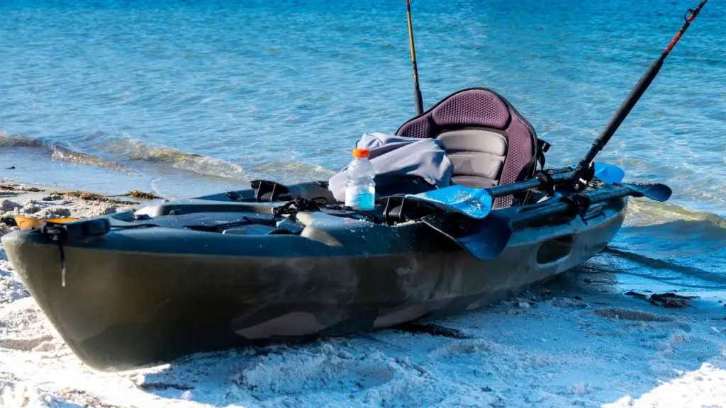 Fully-equipped fishing kayak lying on the sand