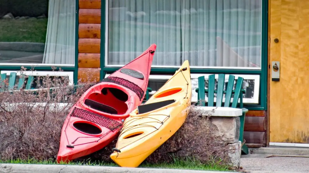 Two red and yellow kayaks are being placed outside the house
