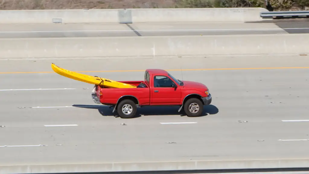 a red truck is carrying a yellow kayak