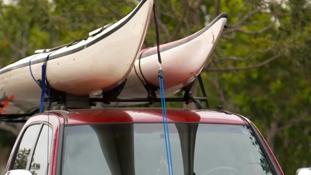 two kayaks being carried by pickup trucks