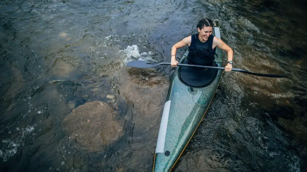 woman is kayaking on a stream