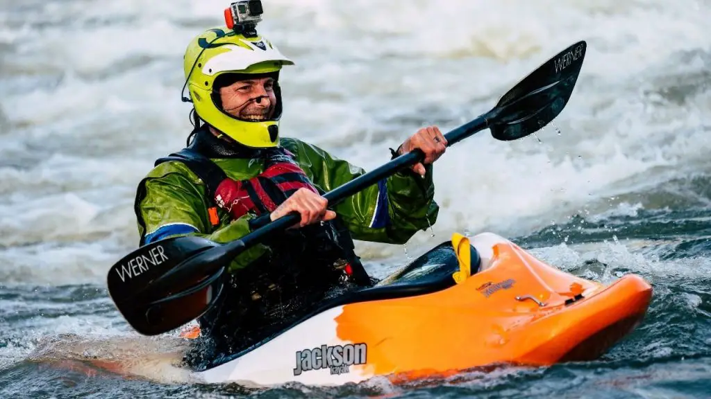 A man is feeling excited and happy while paddling a whitewater kayak