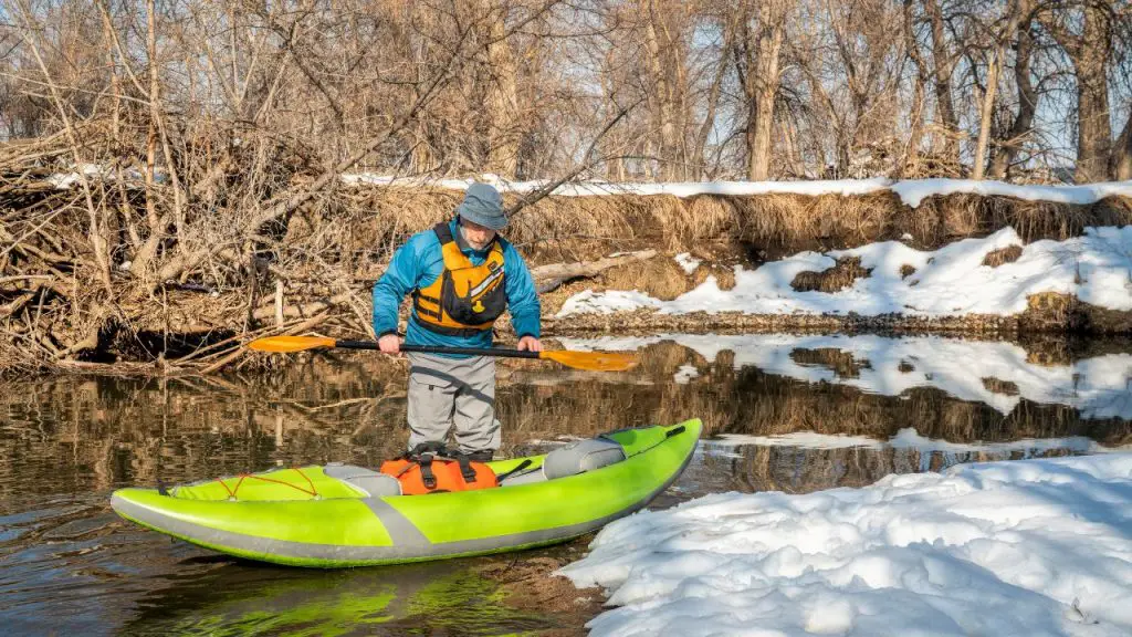 A man is getting into an inflatable kayak.