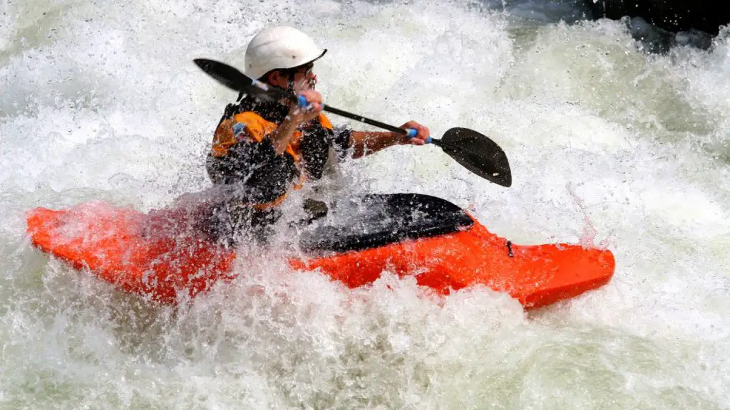 A man is kayaking in tight water