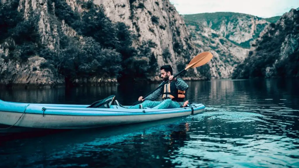 A man is paddling kayak on the lake