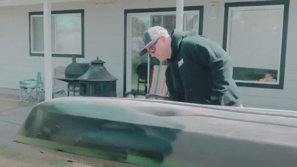 A man is spraying paint on kayak.