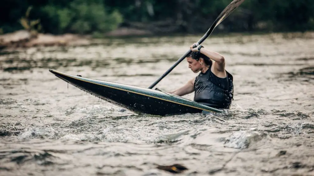 Lady paddles kayak in river