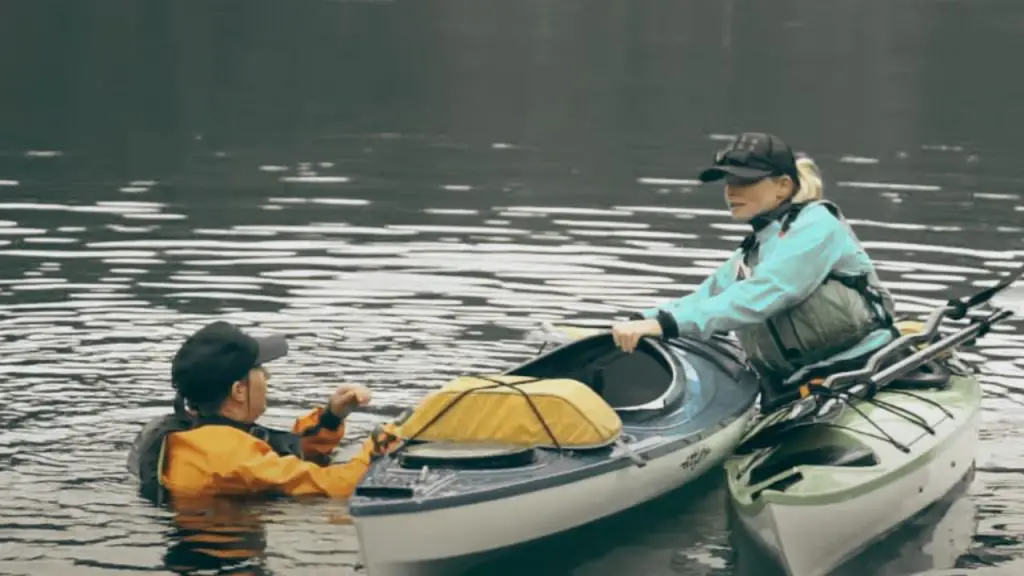 The girl is helping the man to return to the kayak