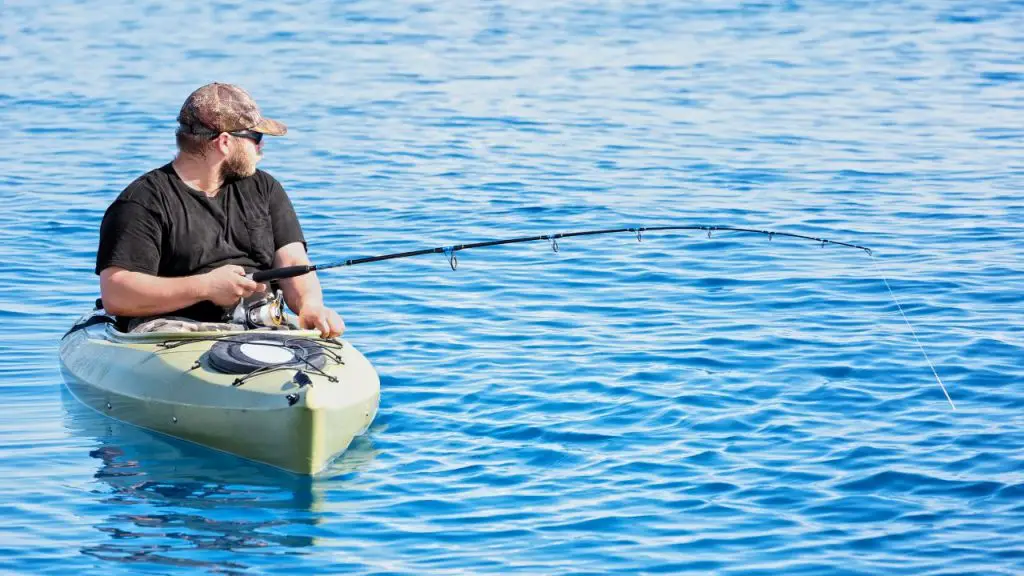 a big guy is fishing on a kayak