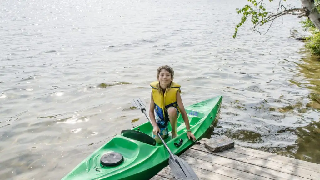 A boy is getting out a kayak sit-on