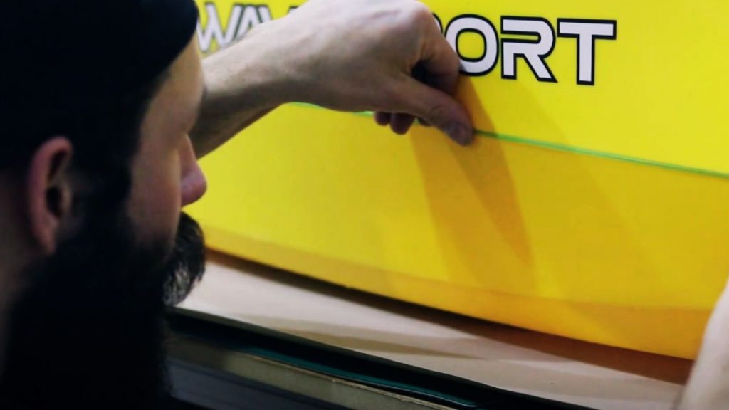 A man is adding wrap-cut tape to kayak.