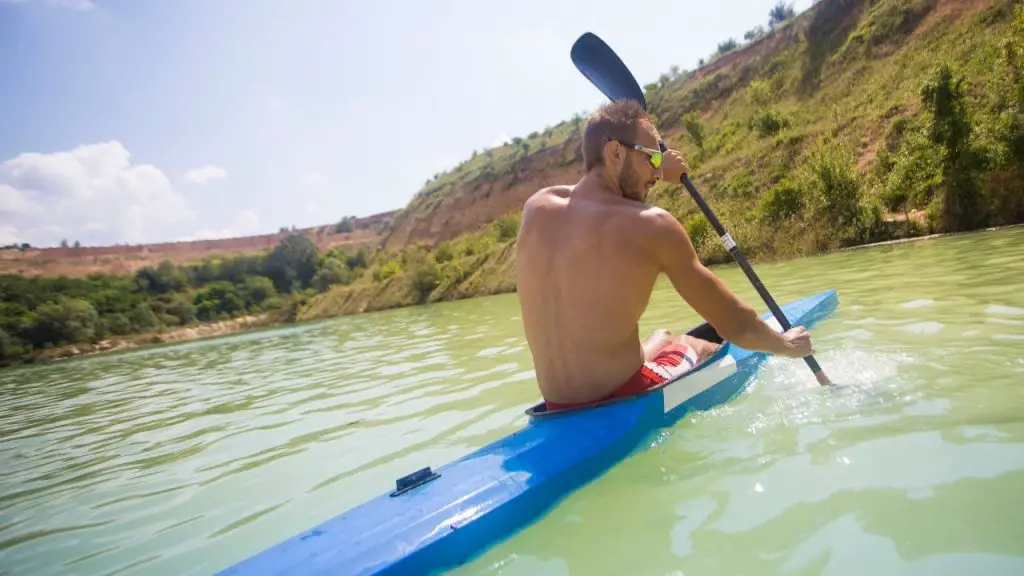 A man is paddling  long and narrow kayak