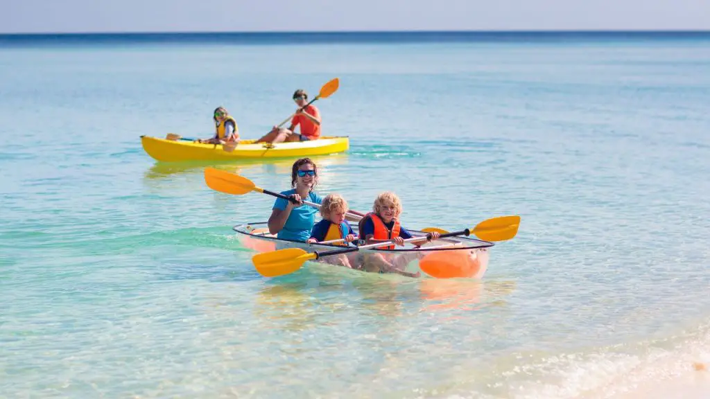 Adults and children are kayaking near shore beach